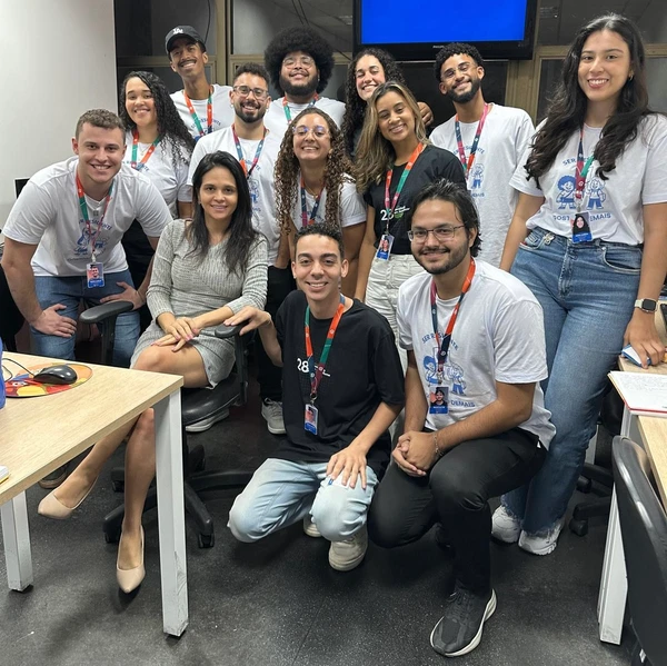 Jornalista Letícia Gonçalves sentada entre alunos do 28º Curso de Residência em Jornalismo.