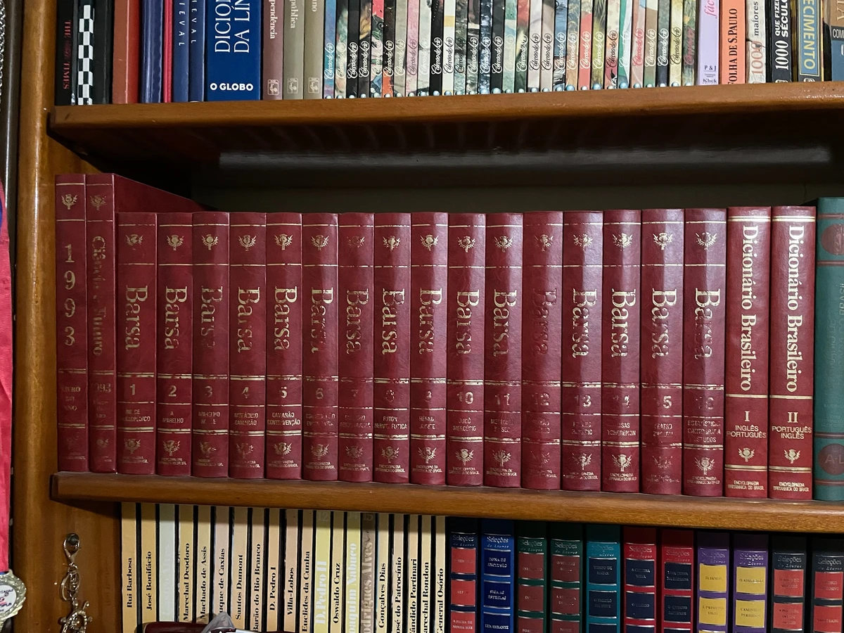 Volumes da enciclopédia Barsa em uma estante de livros.