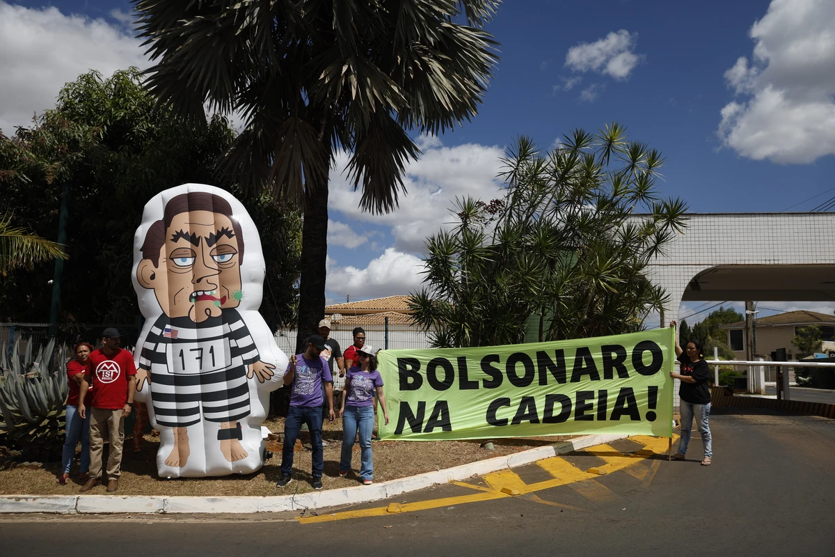 Boneco inflável de Bolsonaro usando uniforme de presidiário e faixa pedindo cadeia foram colocados em frente ao condomínio onde mora ex-presidente em Brasília