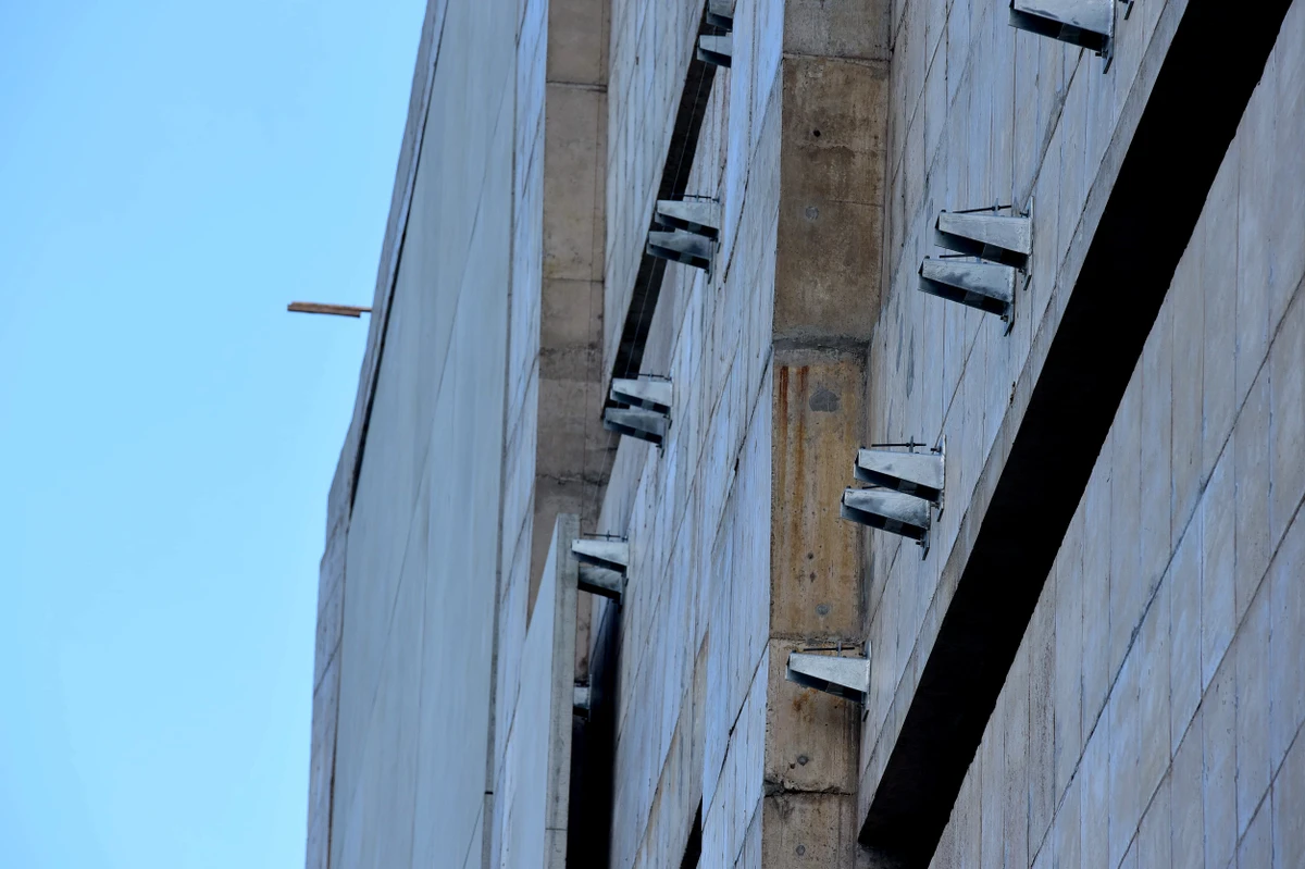 Trabalhadores durante o processo para revestir as parades do Cais das Artes. Primeiro colocam suportes metálicos que vao receber as placas de revestimento. Na foto já aparece parte da parede com as placas. por Carlos Alberto Silva