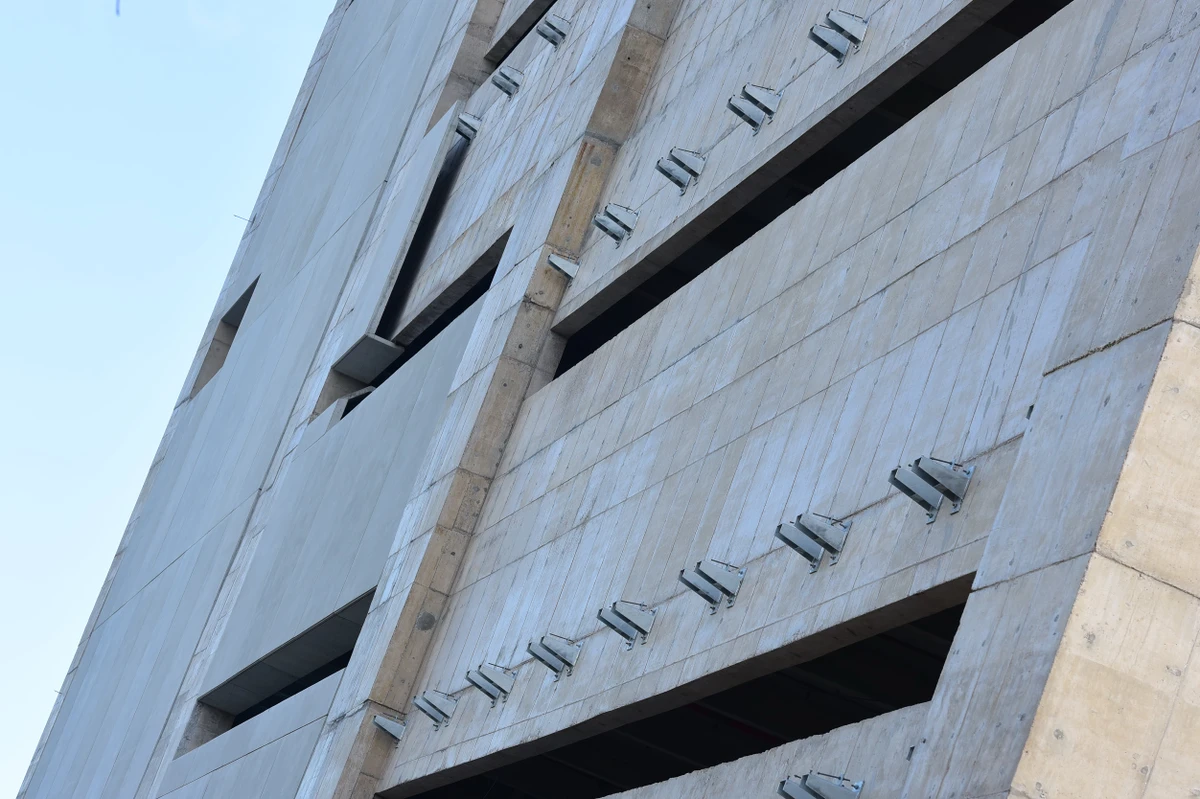 Trabalhadores durante o processo para revestir as parades do Cais das Artes. Primeiro colocam suportes metálicos que vao receber as placas de revestimento. Na foto já aparece parte da parede com as placas. por Carlos Alberto Silva
