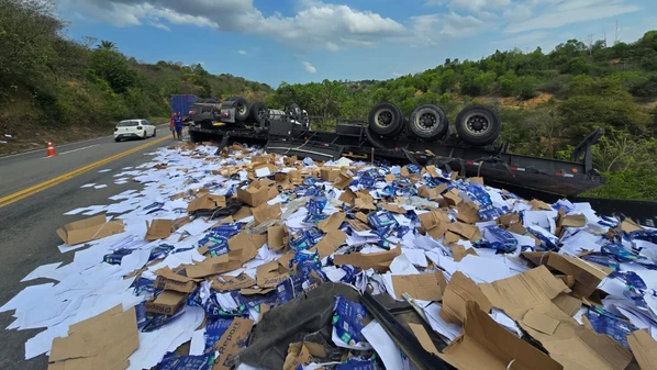 Veículo transportava  caixas de folhas de papel, que ficaram espalhadas pela rodovia; trânsito foi totalmente bloqueado no trecho