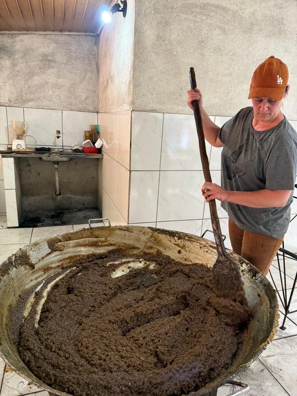 Rosana Bravim mistura no tacho o caldo da cana-de-açúcar, o mamão e o gengibre, matérias-primas do carrapito