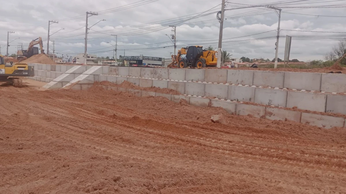 trator na areia e muro feito com blocos