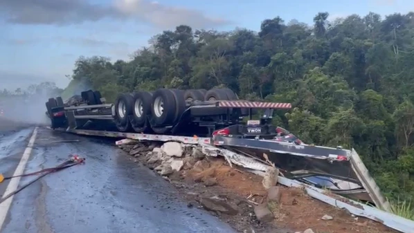 Motorista ficou ferido e foi socorrido; veículo levava uma carga de suporte de televisão de videoconferência quando tombou no km 315 da rodovia