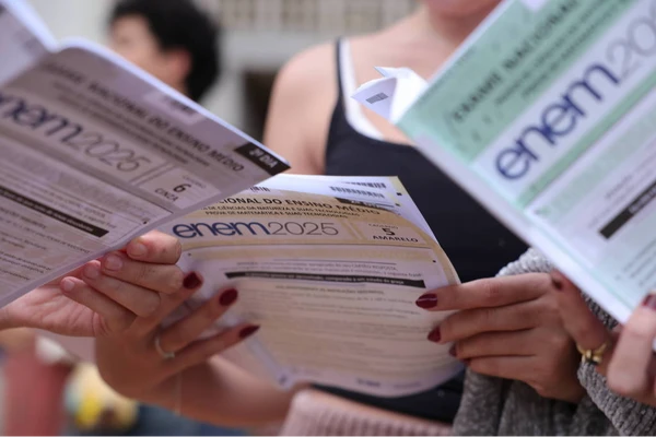 Candidatos olhando os cadernos de questão do segundo dia de aplicação do Enem 2025