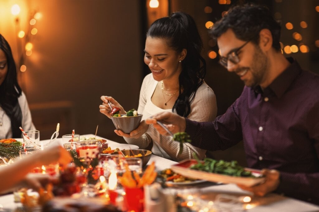 Comer devagar, colocar os talheres no prato entre as garfadas e conversar durante a refeição ajudam a diminuir o risco de exageros (Imagem: Ground Picture | Shutterstock)