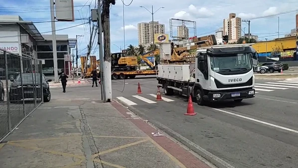 O veículo que transportava duas máquinas pesadas tentou acessar a via e acabou atingindo a estrutura e puxando fios; incidente ocorreu no começo da manhã deste sábado (17)