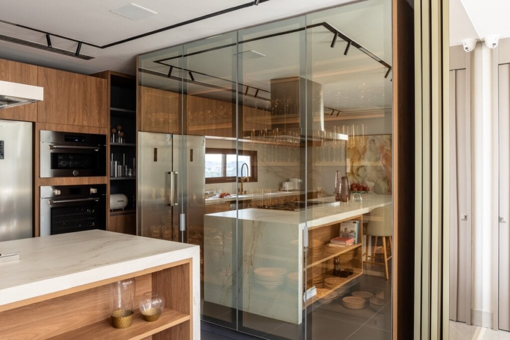 O uso do vidro espelhado valoriza a cristaleira, destaca a iluminação interna e equilibra profundidade e transparência no ambiente (Projeto: Meneghisso &amp; Pasquotto Arquitetura | Imagem: JP Image)