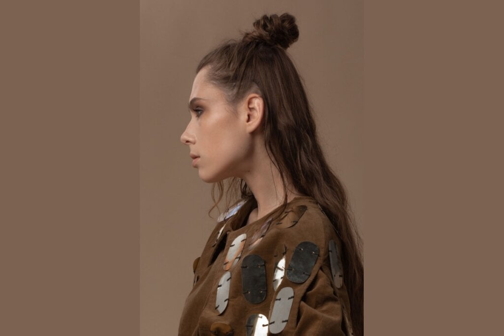 Com parte dos fios presos em um pequeno coque no topo da cabeça, o visual combina praticidade e movimento, mantendo o restante do cabelo solto e cheio de leveza (Imagem: thelavrova | Shutterstock)